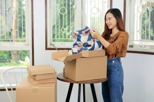 Femme déballant un produit Goldcolis avec un sourire joyeux. Acheter des colis perdus, c’est découvrir des articles inattendus et utiles